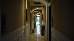 A hallway with white wainscoting and a polished floor leading to a door at the end.