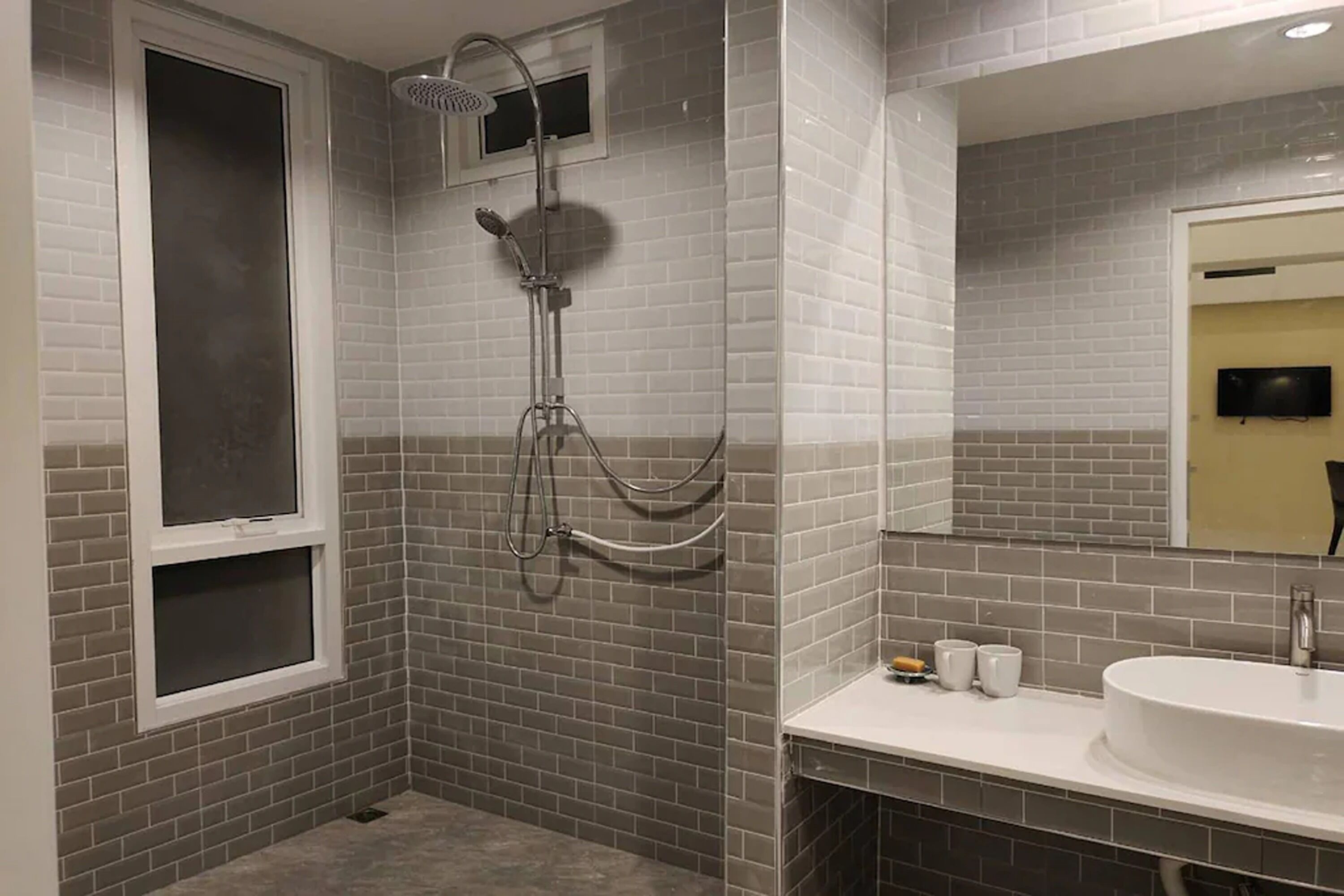 Un bagno con doccia, lavandino e specchio.