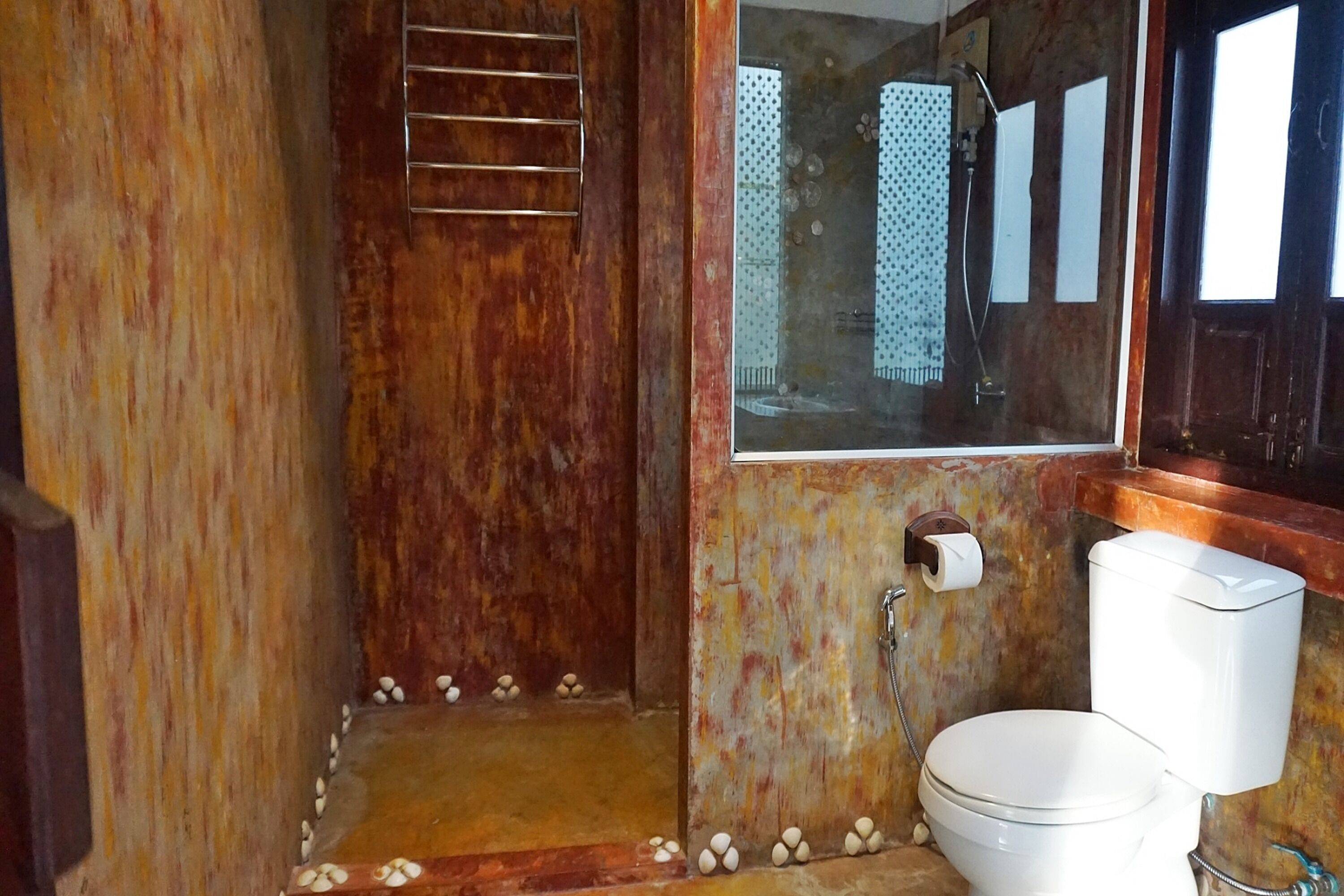 A bathroom with a wooden shower enclosure, a toilet, and a mirror.