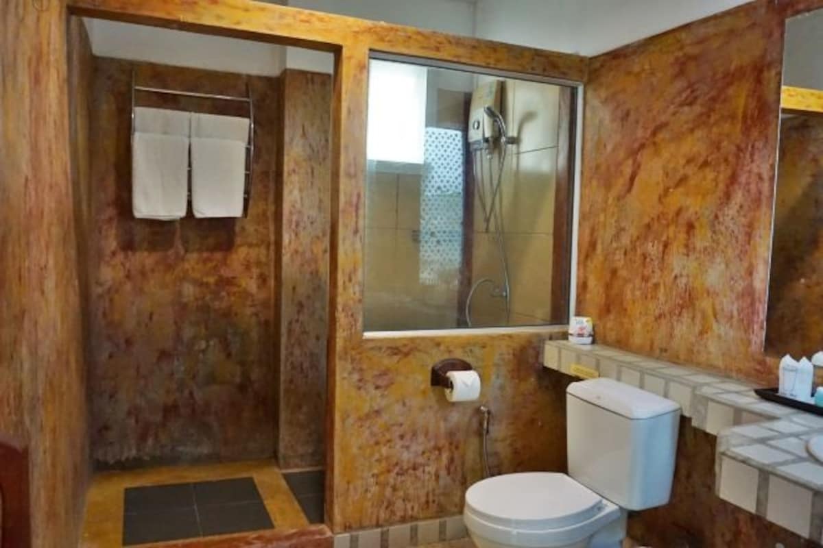 Un baño con pared de mármol, ducha, inodoro y lavamanos.