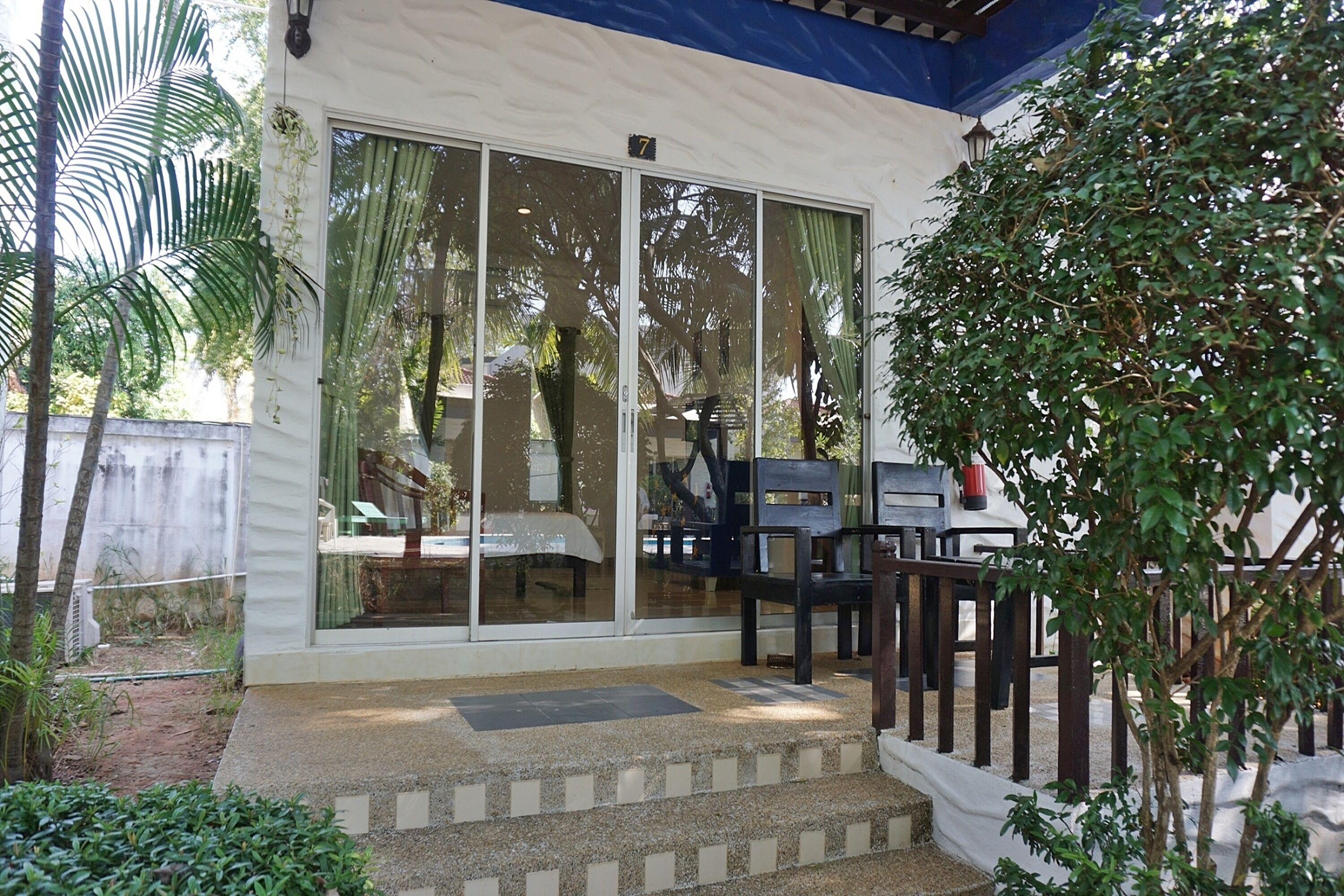 A building with a glass door, a small outdoor seating area, and a staircase leading to the entrance.