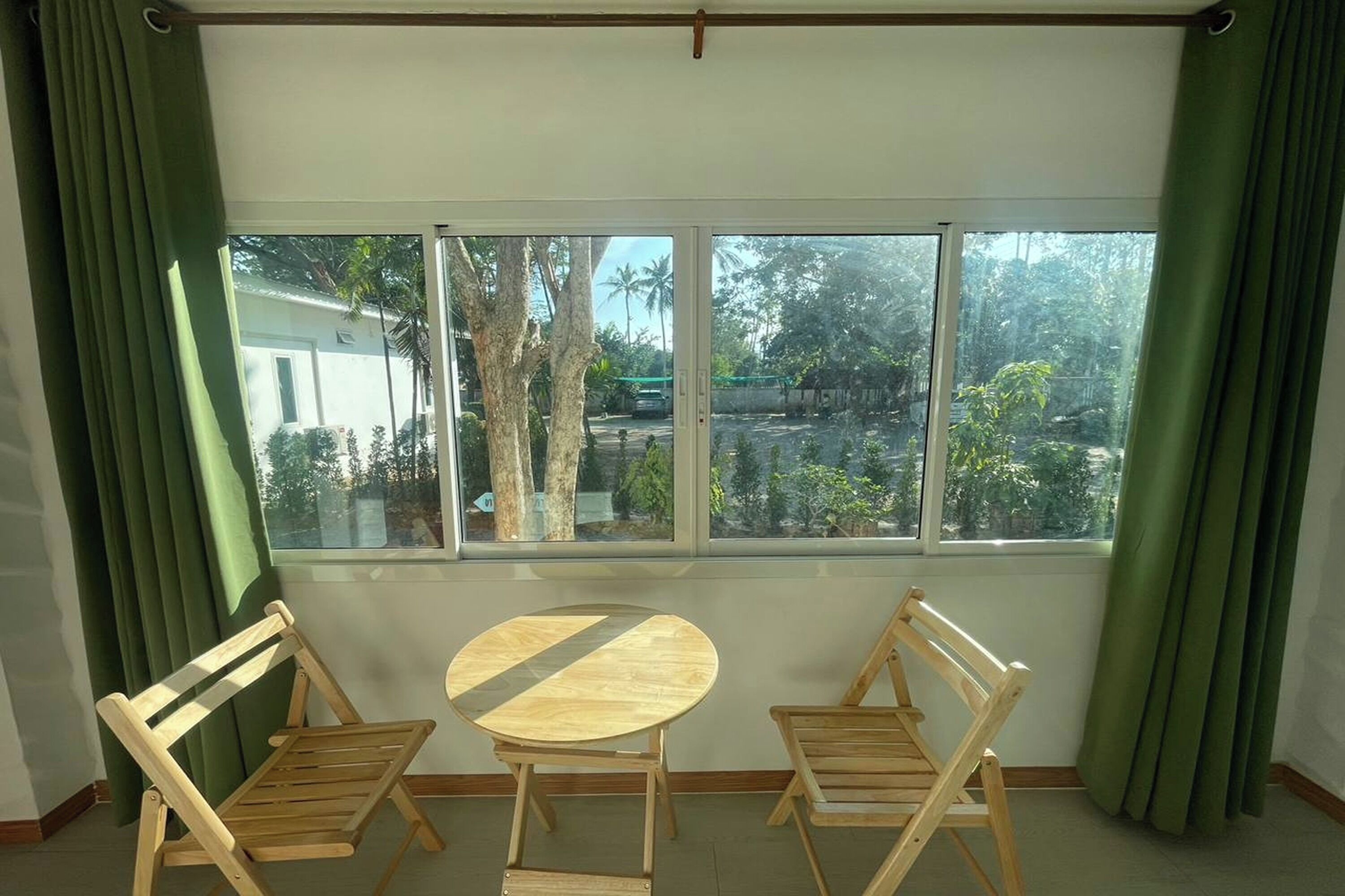 A room with a large window, two wooden chairs, and a small round table.
