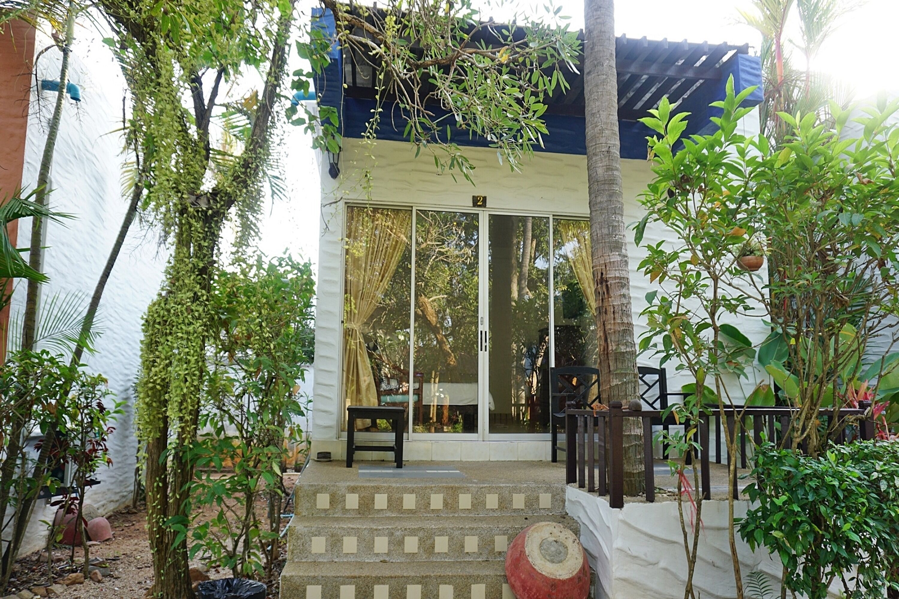 A building with a white exterior, a staircase leading to a door with glass panels, and a small outdoor seating area with a table and chairs.