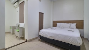 Un dormitorio con cama, una silla y una puerta.