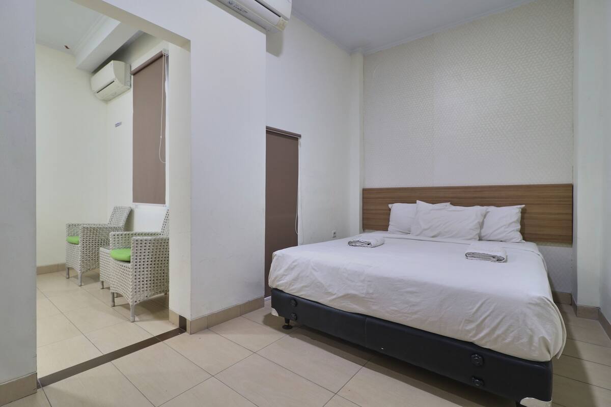 A bedroom with a bed, a chair, and a door.