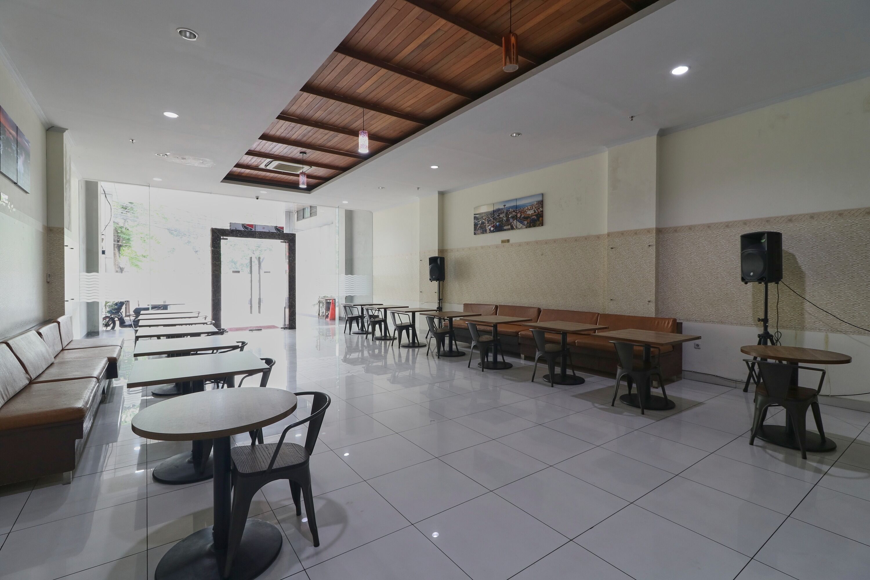 A spacious indoor area with multiple tables and benches, a wooden ceiling, and a large window.