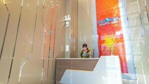 A hotel interior with a reception desk and a large window displaying a vibrant floral design. - Aloha Hotel Quy Nhon (Quy Nhon)