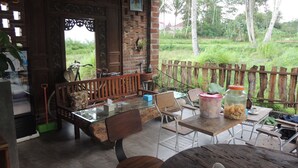 Un área de estar al aire libre rústica con un banco y una mesa de madera, rodeada por una valla de madera y follaje.