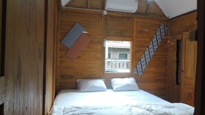 Una habitación de madera con una cama, una ventana y una toalla colgada.