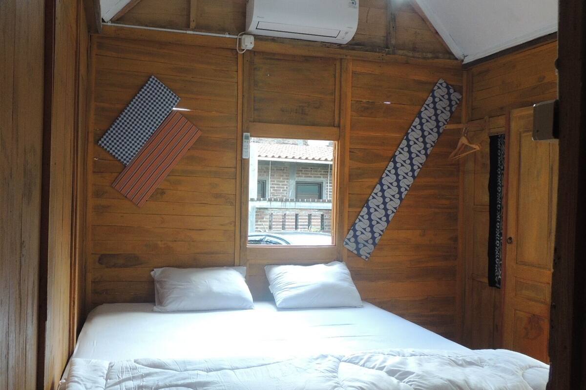 A wooden room with a bed, a window, and a hanging towel.