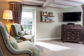 A living room with a sofa, a television, a bookshelf, and a wooden dresser.