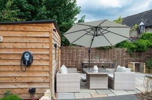A wooden cabin with a power outlet, a large umbrella, wicker furniture, and a stone fireplace.