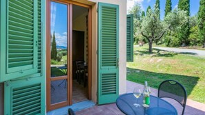 A patio with a table and chairs, a bottle of wine, and a view of trees and a clear sky. - Tipologia Bilo by Interhome (Vinci)