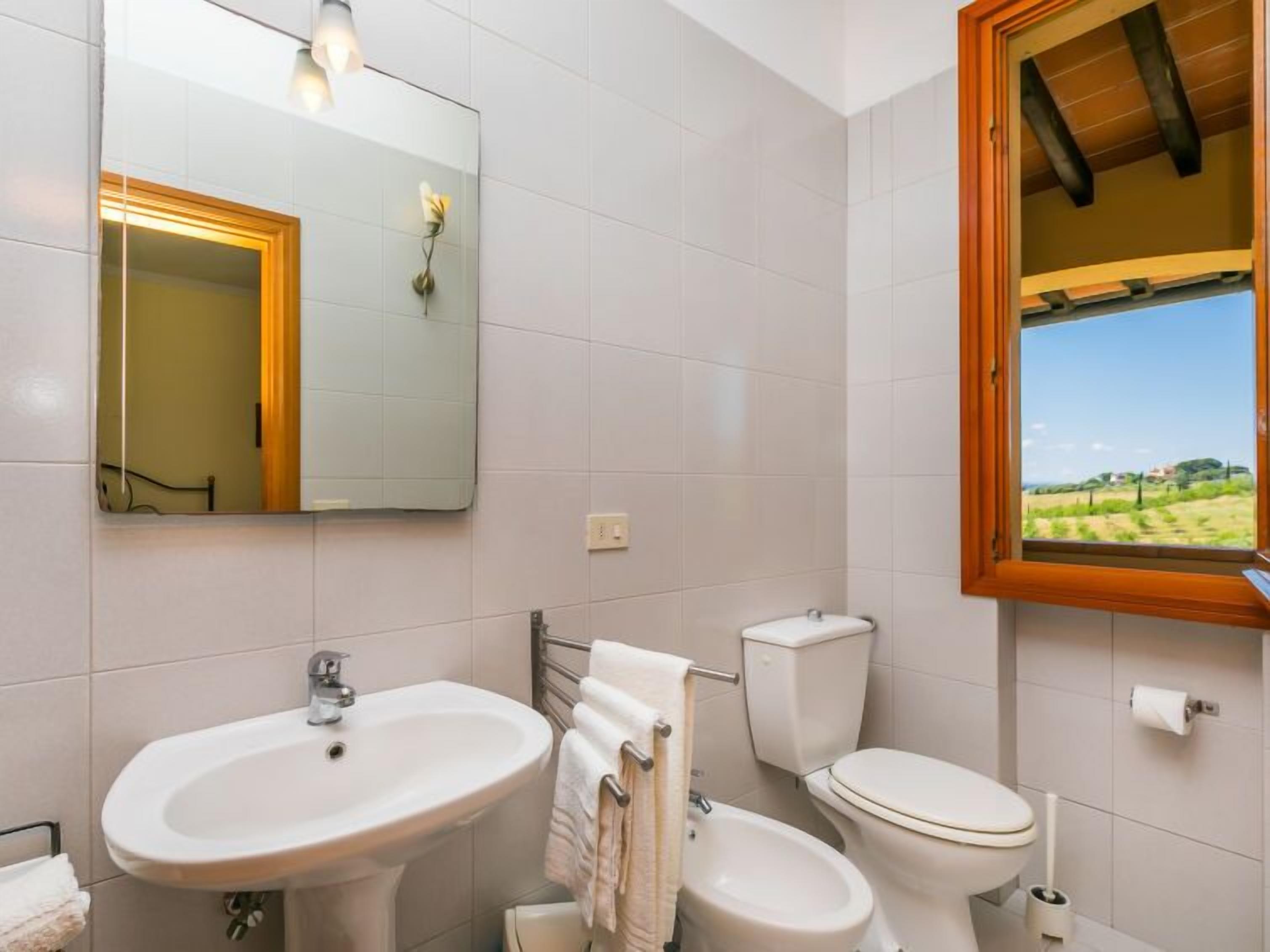 Ein Badezimmer mit Waschbecken, Toilette und einem Spiegel mit Holzrahmen.
