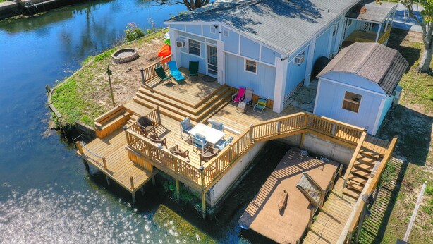 A waterfront house with a deck, a small boat shed, and a dock extending into the water. - 4 Bedroom Farmhouse On The River 2 (Spring Hill)