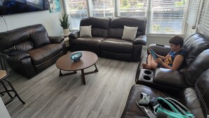 A living room with two leather sofas, a coffee table, and a TV mounted on the wall. - 4 Bedroom Farmhouse On The River 2 (Spring Hill)