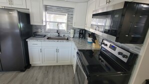 A modern kitchen with white cabinets, a stainless steel refrigerator, a double oven, and a microwave. - 4 Bedroom Farmhouse On The River 2 (Spring Hill)