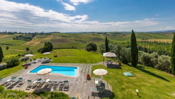 A pool area with lounge chairs and umbrellas, surrounded by lush greenery and rolling hills in the background. - Tipologia Mono by Interhome (Vinci)