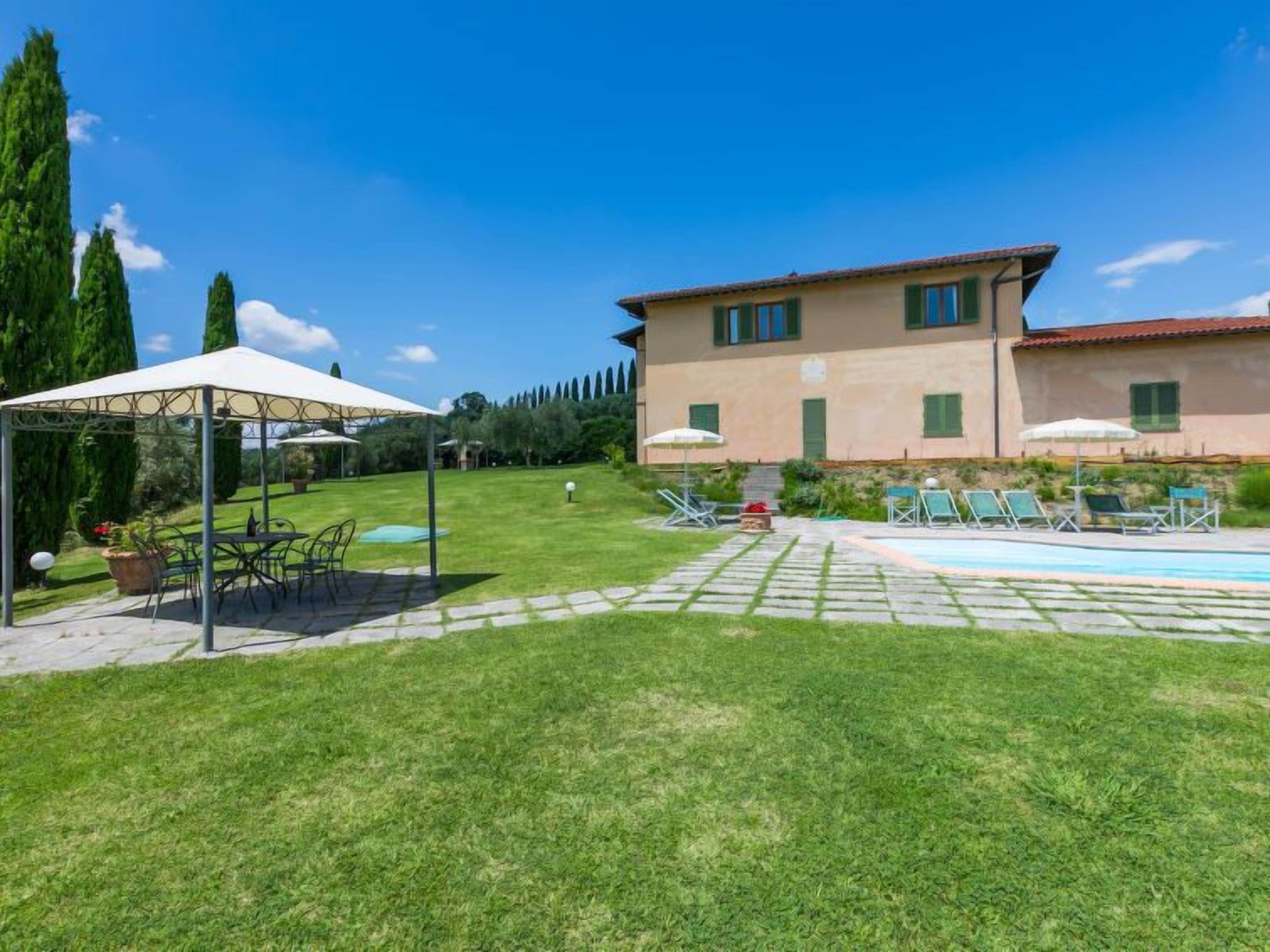 A villa with a swimming pool, outdoor seating, and a well-maintained lawn.