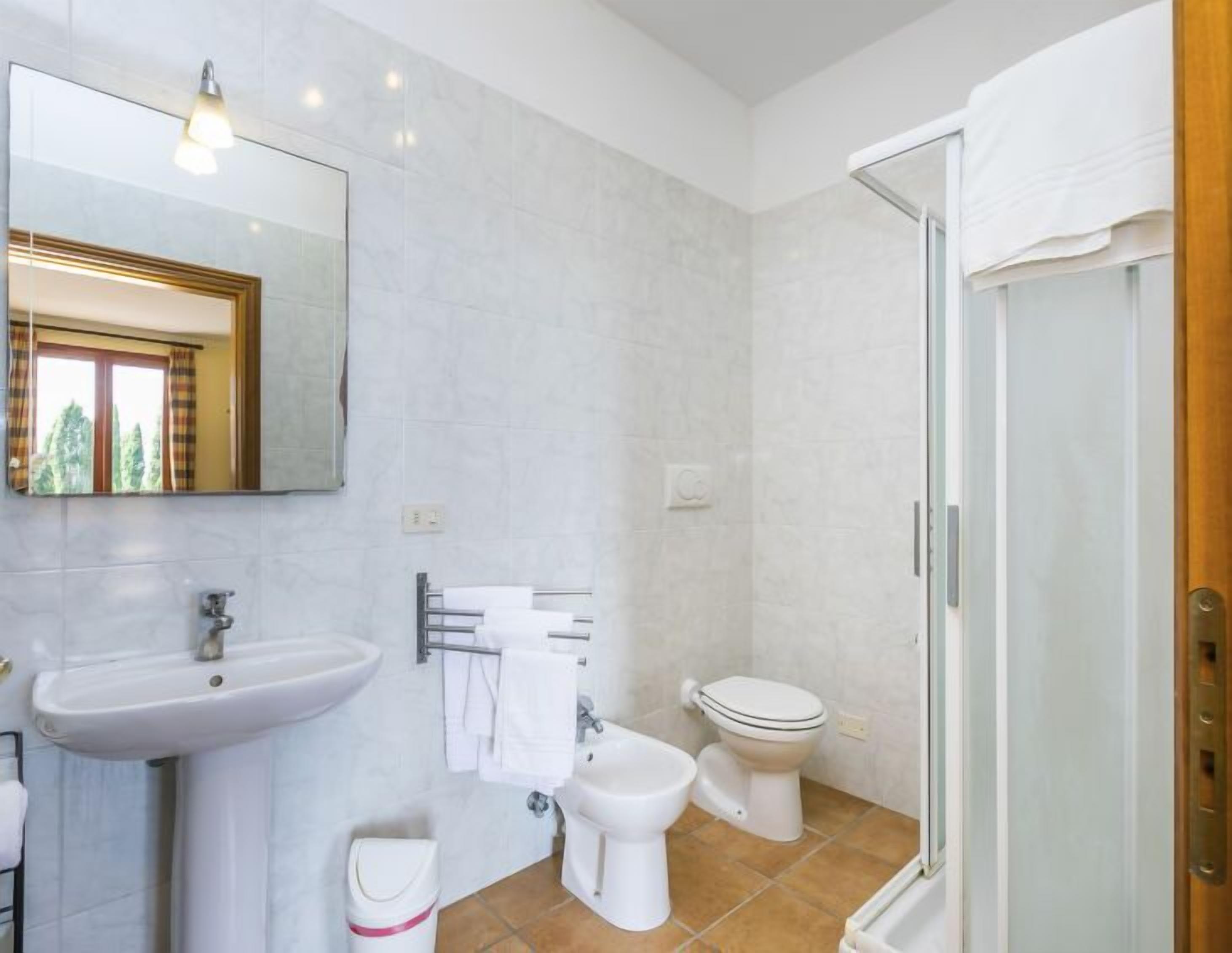 Une salle de bain équipée d’un lavabo, d’un bidet, de toilettes et d’une douche à parois en verre.