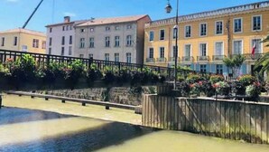 Un canal surmonté d’un pont en bois, des immeubles dotés de balcons et un lampadaire.