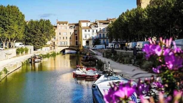 Un canal bordé de bateaux, un pont et des bâtiments le long de la rive.
