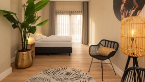A bedroom with a bed, a potted plant, a chair, a lamp, and a wall-mounted artwork. - Familieboerderij by Interhome (Losser)