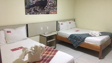A hotel room with two beds, a small table, and a wall-mounted picture.