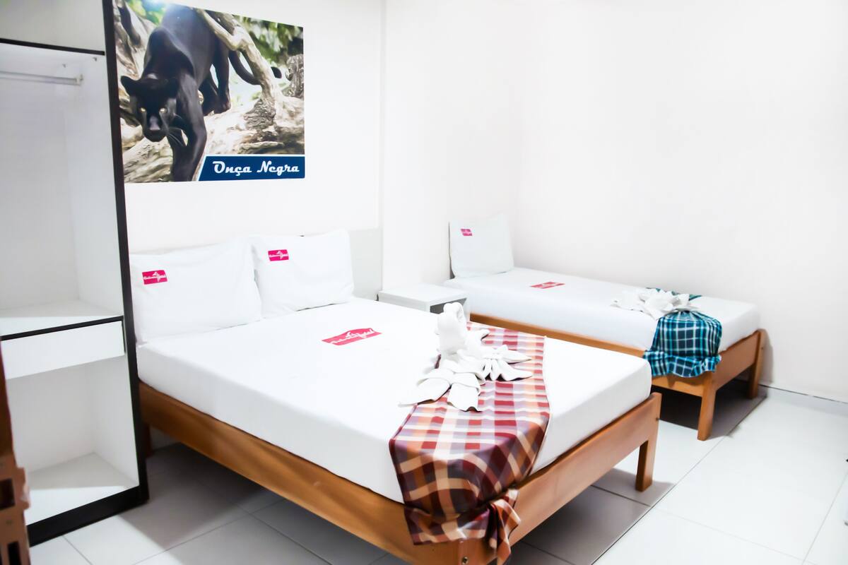 A hotel room with two beds, white bedding, and a checkered blanket on one bed.