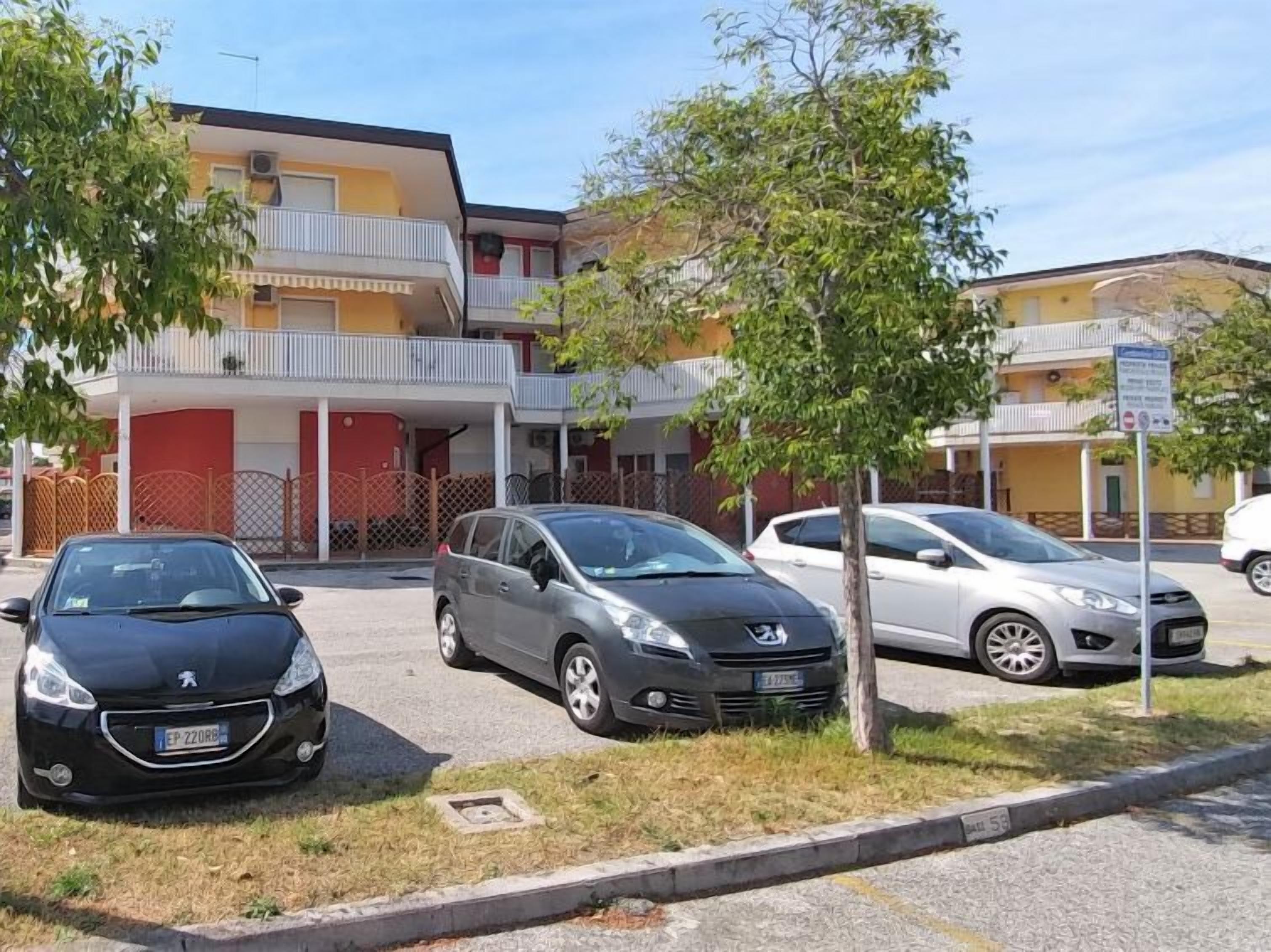 Un estacionamiento con tres coches aparcados frente a un edificio con balcones.