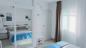 Ein modernes Schlafzimmer mit Bett, Kleiderschrank, Nachttisch und einem Fenster mit Vorhängen.