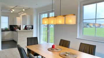 Une cuisine moderne avec des meubles blancs et un coin repas comprenant une table et des chaises en bois.