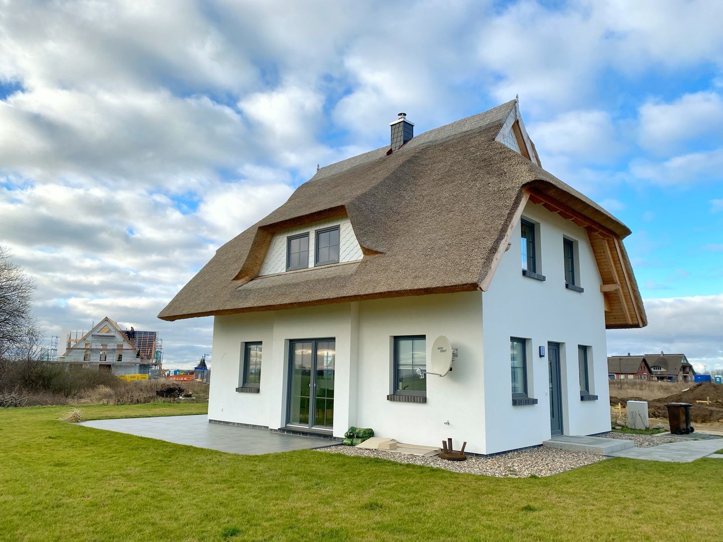 A modern two-story house with a steeply pitched roof, large windows, and a well-maintained lawn.