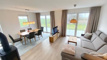 A modern living room with a sofa, TV, dining table, and chairs.