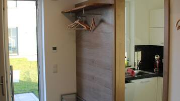 Een modern interieur met een houten wand, een metalen plank en een keukenruimte zichtbaar door een open deur.
