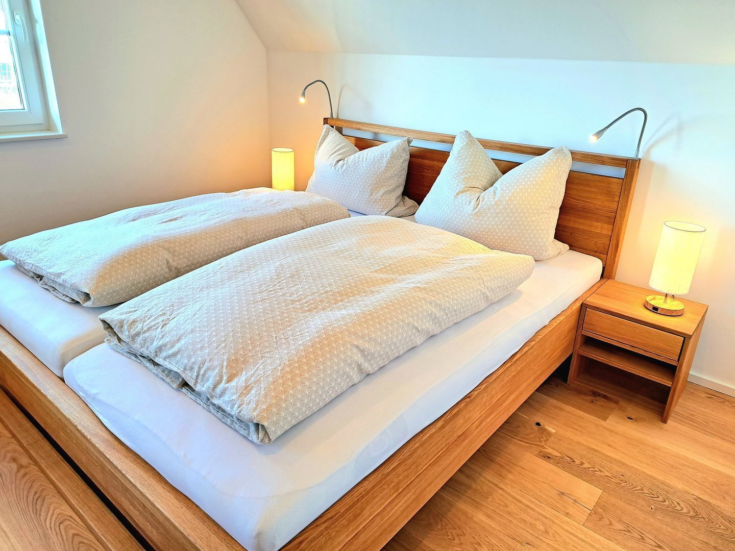 Un lit bien fait, avec deux oreillers, une tête de lit en bois et une table de chevet avec une lampe.