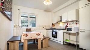 A kitchen with white cabinets, a microwave, a stove, and a window. - Holiday Apartment 'Nguyen Und Le 2' with Wi-Fi (Neukirch)