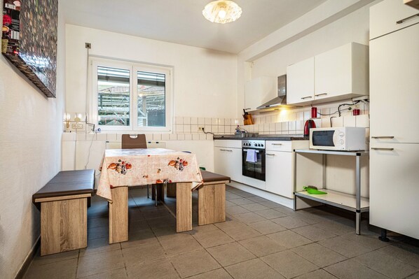 A kitchen with white cabinets, a microwave, a stove, and a window.