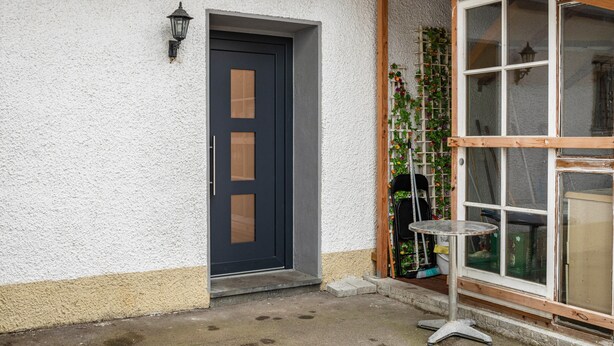 A house with a dark door, a small table, and a window with a wooden frame. - Holiday Apartment 'Nguyen Und Le 2' with Wi-Fi (Neukirch)