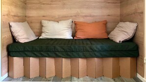 Un coin salon avec un banc en bois, trois coussins et un coussin vert.