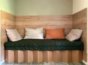 A corner seating area with a wooden headboard, three pillows, and a green cushion.