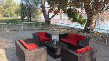 An outdoor seating area with wicker furniture and red cushions.