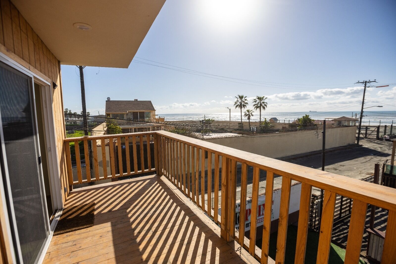 Un balcon en bois offrant une vue sur la plage et l’océan.