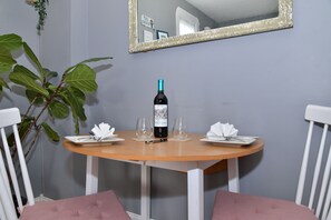 Una mesa redonda de madera con una botella de vino, dos copas y un plato con una servilleta.