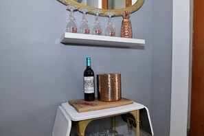 Una botella de vino, un recipiente de cobre y un espejo sobre una estantería.