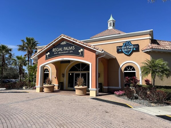 A building with a sign for Regal Palms Bar, Restaurant, and Spa, and another sign for Frankie & Farrall's Pub & Grill.