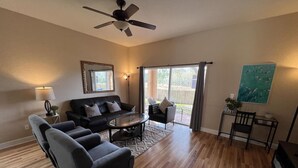 Un salon comprenant un canapé, des fauteuils, une table basse et un ventilateur de plafond.