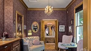 Una habitación elegante con candelabro, tocador con espejo, sofá confortable y zona de comedor con mesa y sillas.
