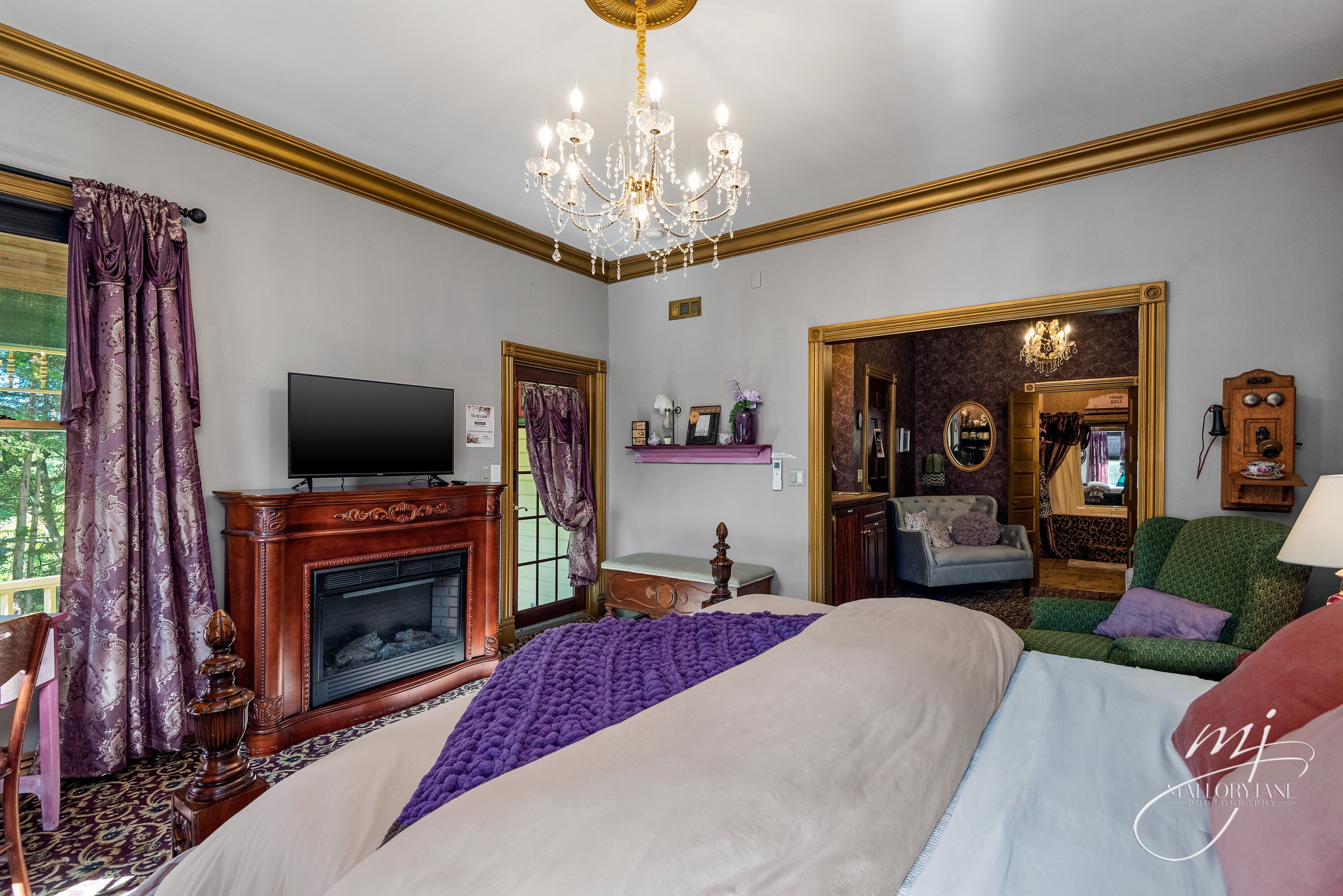 Ein Schlafzimmer mit einem großen Bett, einem Kamin, einem Fernseher und einer Kristallleuchtre.