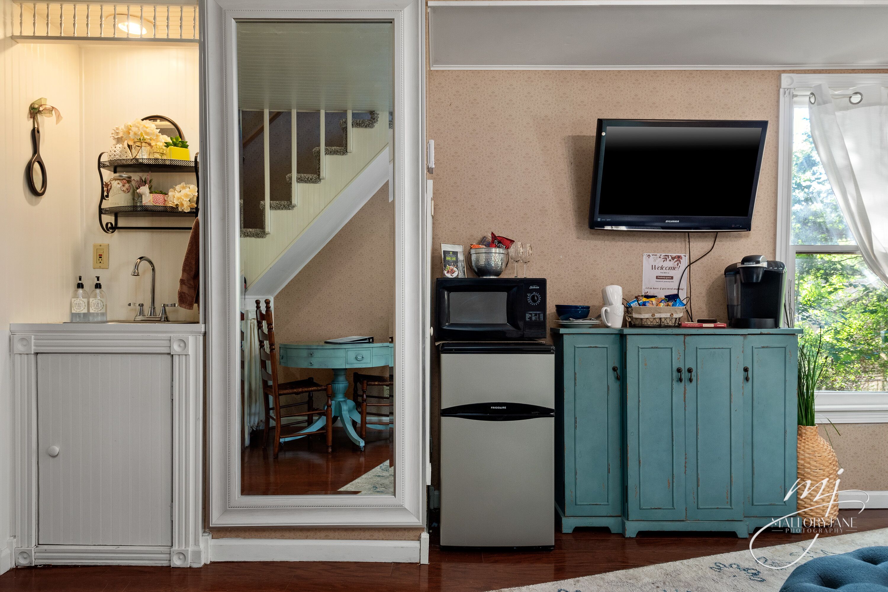 A kitchen with a refrigerator, microwave, and a television on the wall.